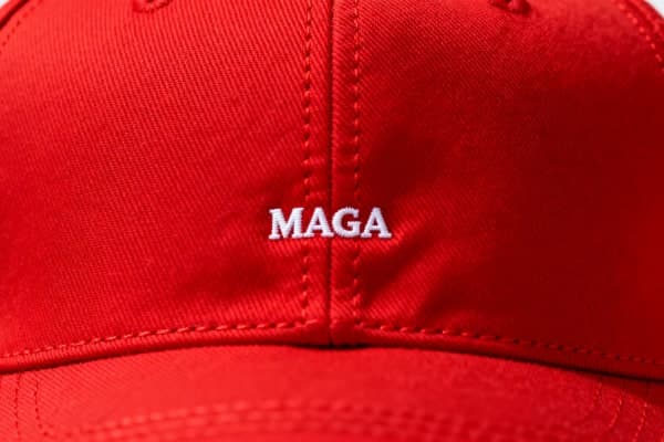 Close-up of a red baseball cap with the word “MAGA” stitched in small white lettering at the centre.